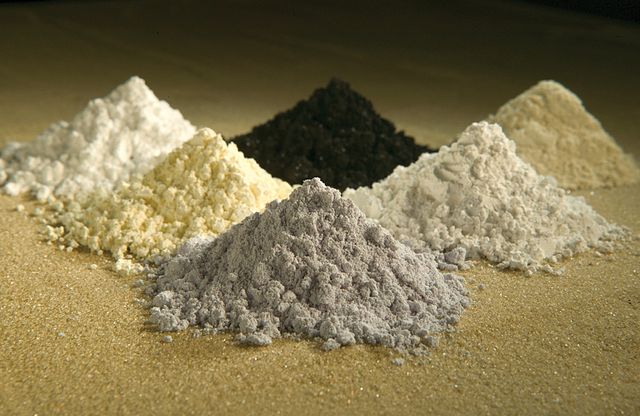 Poudres de six oxydes de terres rares. Dans le sens des aiguilles d'une montre à partir d'en haut à gauche : gadolinium (blanc), praséodyme (noir), cérium (beige), lanthane (blanc), néodyme (gris) et samarium (blanc jaune).